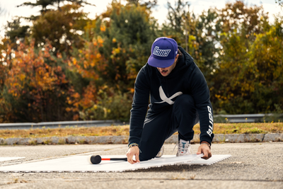 Bauer Dryland Training Tiles 10 Pack person outside kneeling while connecting a tile to others